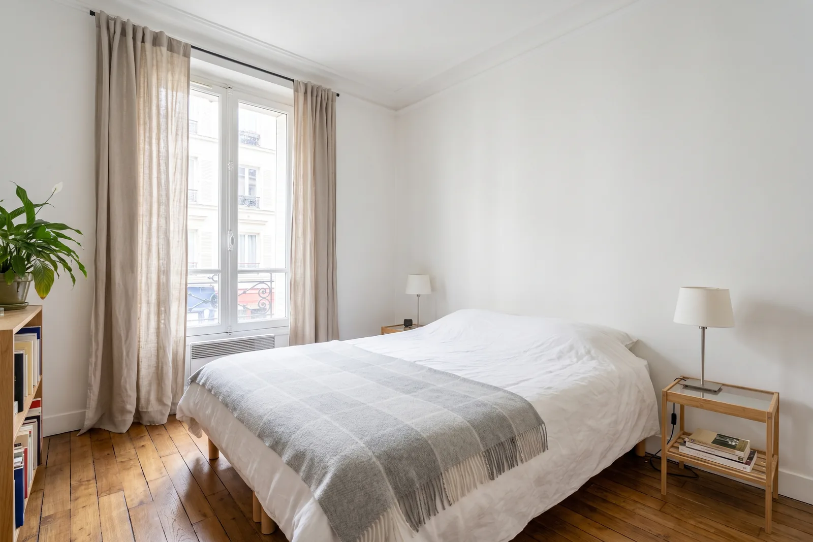 Chambre au linge clair et au chevet dégagé, prête à être photographiée