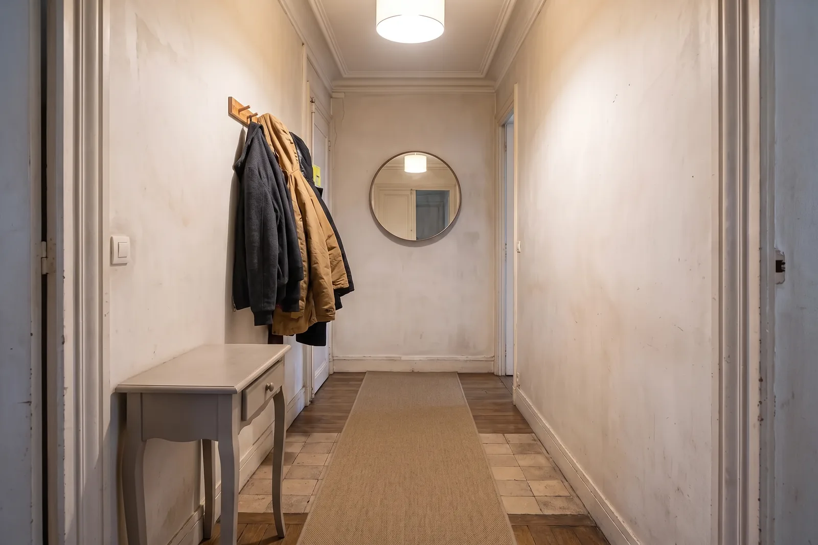La même entrée rangée, avec un miroir et un tapis, après le home staging